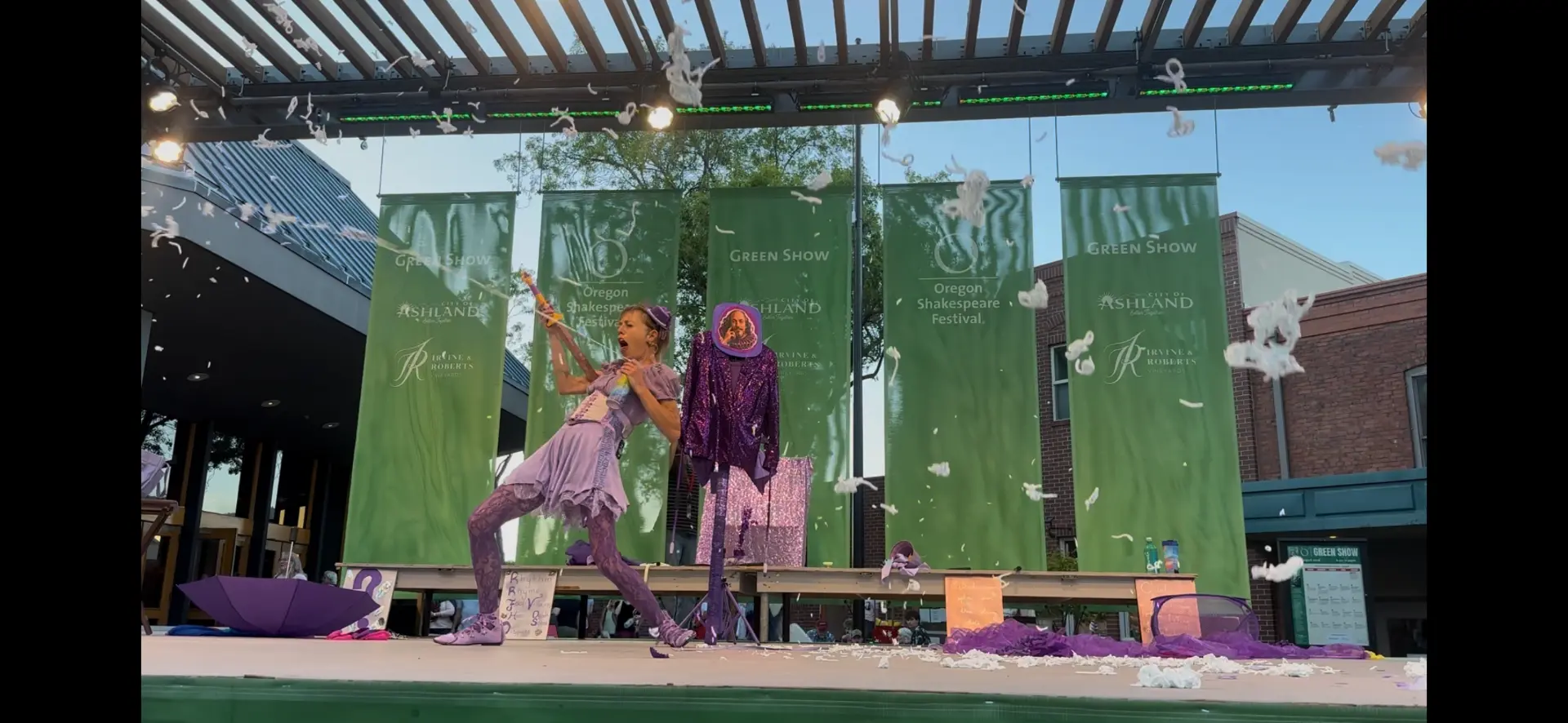 Feathers flying through the air as Jenifer Joy performs on the Oregon Shakespeare Festival Green Show stage