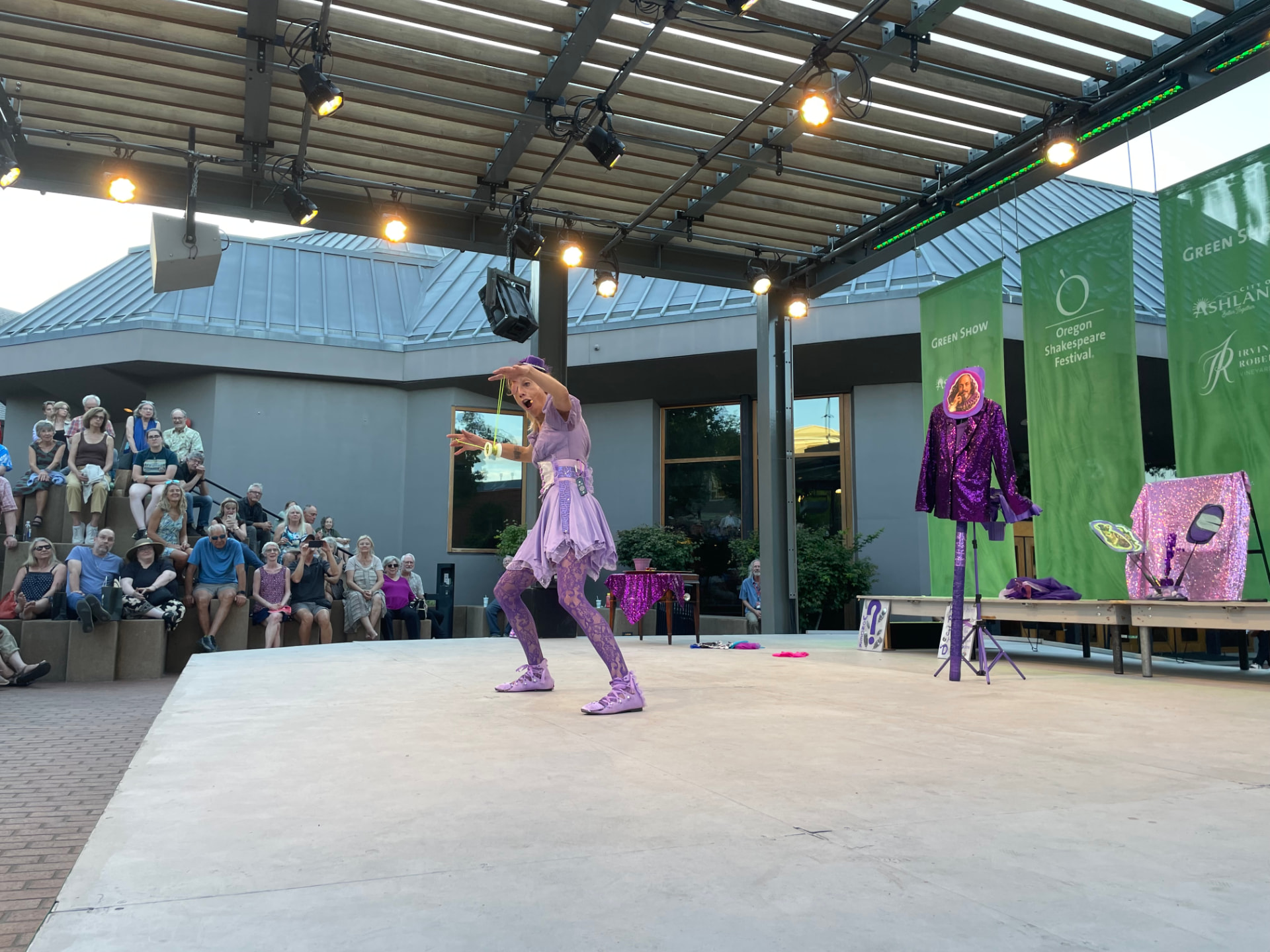 Jenifer Joy on stage beside the Shakespeare costume stand and Oregon Shakespeare Festival banners